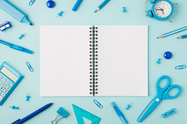 Foto de vista superior del libro de trabajo abierto en el medio y papelería azul sobre fondo azul pastel aislado con espacio de copia