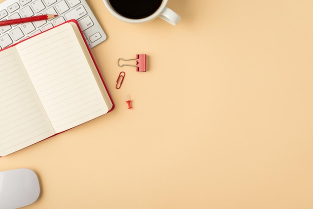 Foto de la vista superior del papelería del mouse del teclado blanco, pin de clip de carpeta de lápiz de recordatorio rojo abierto y taza de café sobre fondo beige aislado con espacio de copia