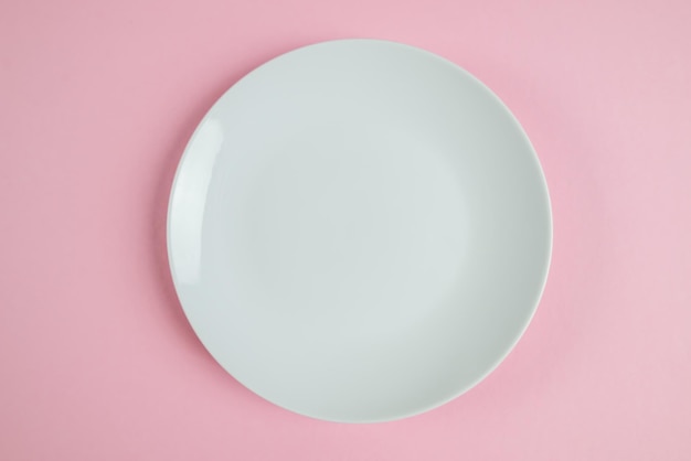 Foto de vista superior de plato blanco sobre fondo rosa pastel aislado