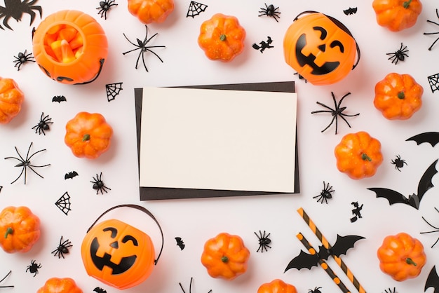 Foto de vista superior de sobre negro tarjeta blanca cestas de calabaza pajitas de maíz dulce arañas web y siluetas de murciélagos sobre fondo blanco aislado con espacio vacío