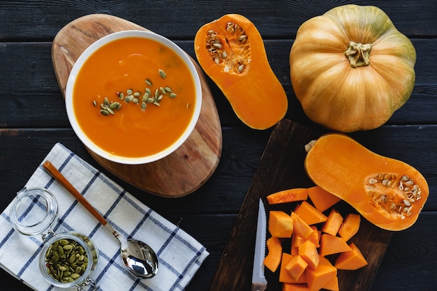 Foto de la vista superior de sopa de calabaza hecha puré en un recipiente blanco sobre la mesa oscura