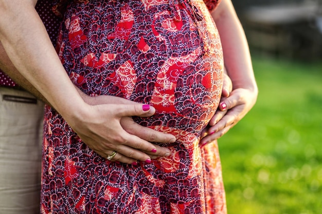 Foto von Bauch der schwangeren Frau Hände umarmen schwangeren Bauch Nahaufnahme von menschlichen Händen halten schwangeren Bauch Schwangere Frau umarmt ihren Bauch Schwangerschaft Schwangerschaft Konzept
