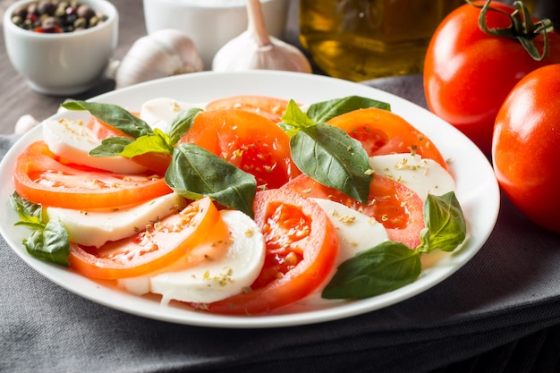 Foto von caprese-salat mit tomaten, basilikum, mozzarella, oliven und olivenöl