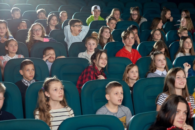 Foto von den lustigen Kindern, die Film im Kino aufpassen.