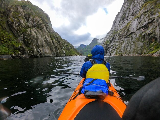 Foto von der Rückseite einer Touristin mit Paddelkanu, das den Fluss entlang schwimmt