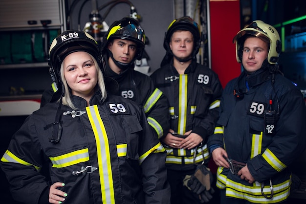 Foto von drei Feuerwehrmännern und lächelnder Frau auf dem Hintergrund des Feuerwehrautos