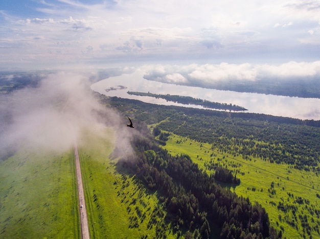 Foto von einer Drohne eine Straße in die Ferne vor dem Hintergrund eines großen Flusses und eines grünen Waldes