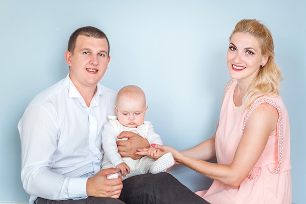 Foto von Eltern mit einem kleinen Kind posieren gegen die blaue Wand