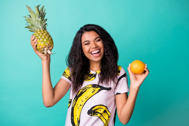 Foto von energischen Mädchen halten Ananas orange tragen rosa T-Shirt isoliert über türkisfarbenem Hintergrund