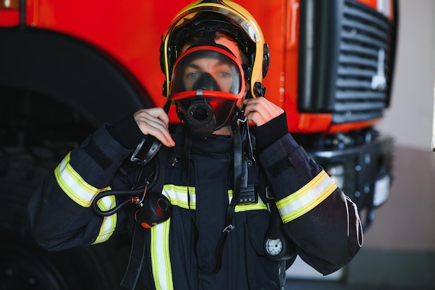 Foto von Feuerwehrmann mit Gasmaske und Helm in der Nähe von Feuerwehrauto
