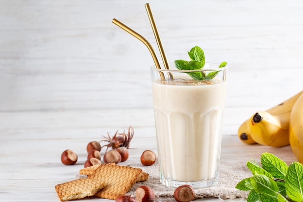 Foto von frischem Bananen-Smoothie auf einem Holztisch mit Keksen und Banane. Milchshake. Protein-Diät. Gesundes Lebensmittelkonzept, Platz für Text.