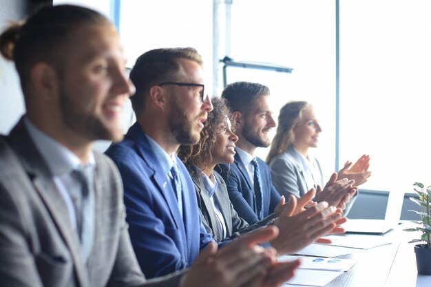 Foto von glücklichen Geschäftsleuten, die bei der Konferenz applaudieren.