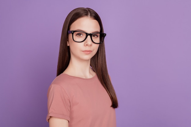 Foto von klugem Teenager-Mädchen in Gläsern, die gut aussehend auf violettem Hintergrund isoliert sind?