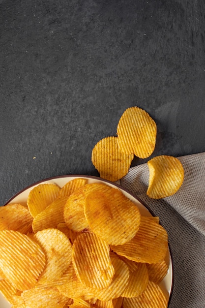 Foto foto von knusprigen kartoffelchips von oben auf dunklem hintergrund mit platz für text