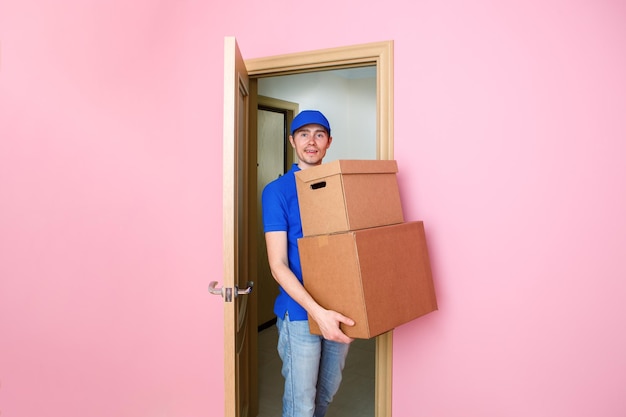 Foto von Kuriermann in blauer Baseballkappe mit Kartons in den Händen