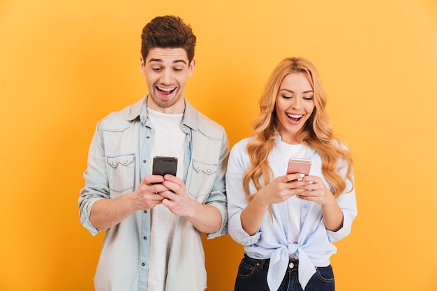 Foto von Mann und Frau der aufgeregten Leute lächelnd, während beide Handys benutzen