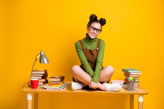 Foto von positivem High-School-Geek-Mädchen sitzen Tischbeine gekreuzt Genießen Sie akademische Studiengänge