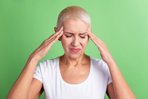 Foto von reifen Frauenarmen berühren Kopfschmerz-Krankheitssymptom Coronavirus einzeln auf grünem Hintergrund.