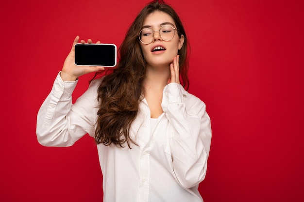 Foto von sexy schöne junge brünette Frau mit weißem Hemd und optischer Brille isoliert über