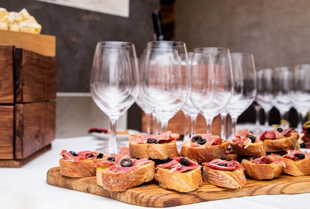 Foto von Snacks mit Schinken auf dem Banketttisch und Gläsern Wein