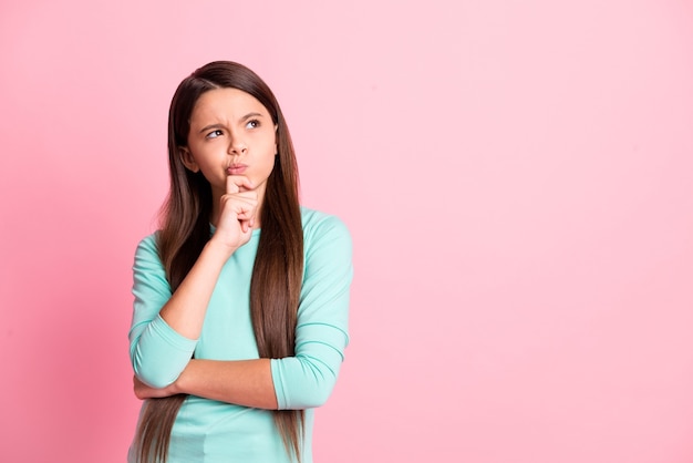 Foto von süßen schönen kleinen zweifelhaften schwerfälligen hispanischen Dame lange Frisur Hand Finger Kinn Blick auf leeren Raum gekreuzte Hände tragen türkisfarbenes Sweatshirt isoliert rosa Farbhintergrund