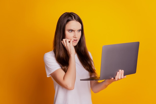 Foto von wütender Dame, die Laptop hält, hat Probleme, weißes T-Shirt zu tragen, das auf gelbem Hintergrund posiert