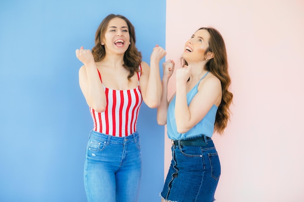 Foto von zwei emotionalen Freundinnen, die isoliert vor farbigem Hintergrund stehen
