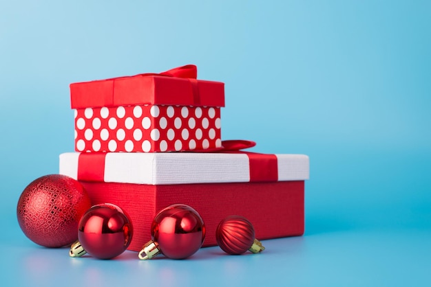 Foto von zwei Geschenkkartons und vier rot glänzenden Kugeln auf blauem Hintergrund isoliert