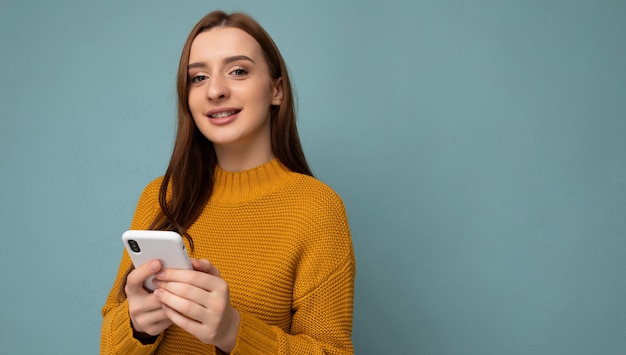 Fotoaufnahme der attraktiven positiven gut aussehenden jungen Frau, die lässiges stilvolles Outfit Poising trägt