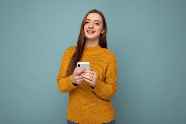 Fotoaufnahme der attraktiven positiven gut aussehenden jungen Frau, die lässiges stilvolles Outfit Poising trägt