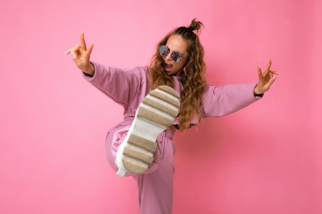 Fotoaufnahme der jungen schönen attraktiven netten lustigen positiven lockigen blonden Frau, die modische und