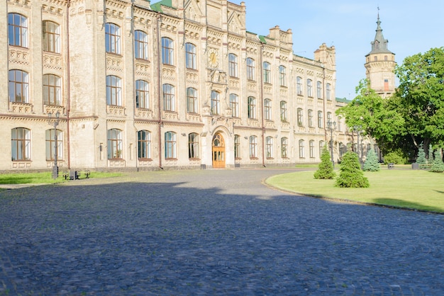 Fotobild des alten Universitätsgebäudes mit grünem Park bei Sonnenaufgang