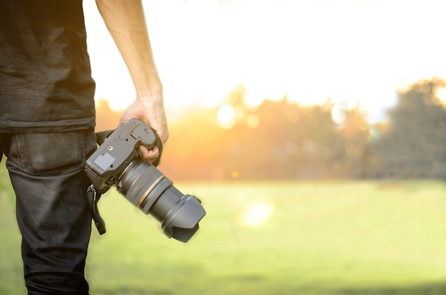 Fotograf, der eine Kamera in der Hand im Sonnenunterganghintergrund hält