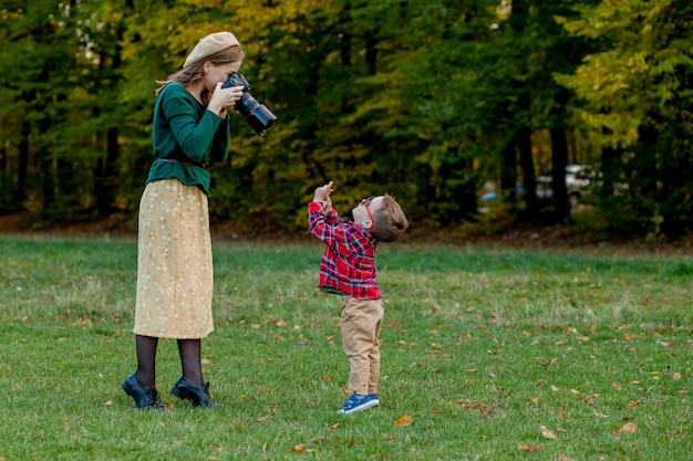 Fotograf der Frau, die das Kind fotografiert, um draußen im Park zu verbringen.