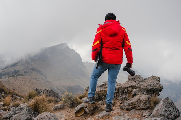 Fotograf des jungen Mannes, der Digitalkamera in den Bergen hält
