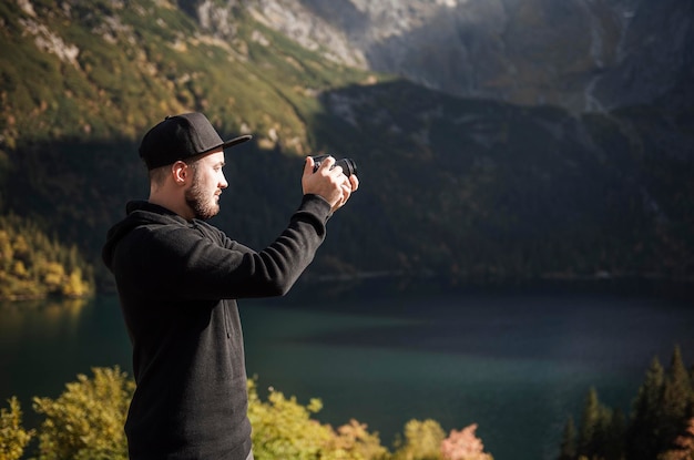 Fotograf des jungen Mannes, der Fotos mit Digitalkamera in einem Gebirge macht