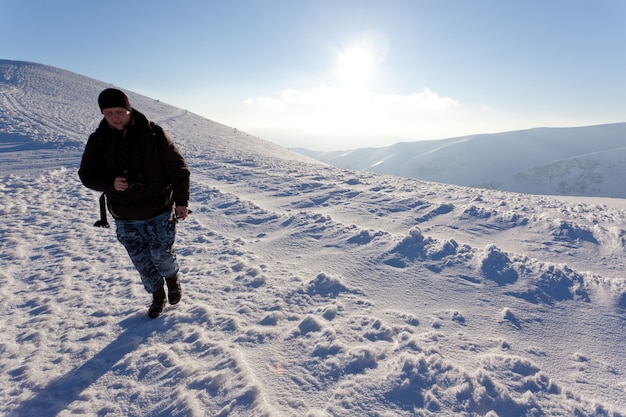 Fotograf des jungen Mannes in der Winterkleidung stehend und Foto im Sonnenlicht machend