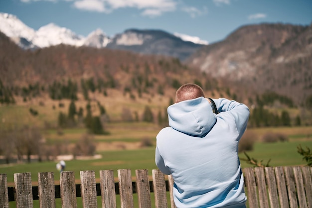 Fotograf mit einer Kamera macht ein Bild von den Schneebergen gegen den blauen Himmel in den Alpen Wanderlust-Konzept