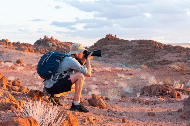 Fotograf unter Foto in den Felsen der Namib-Wüste Namibia Afrika Rote Berge und Sonnenuntergang Himmel im Hintergrund Landschaftsfotografie