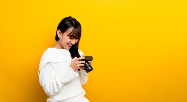 Fotógrafa asiática Mira las fotos de la cámara con una sonrisa feliz. concepto de fotografía