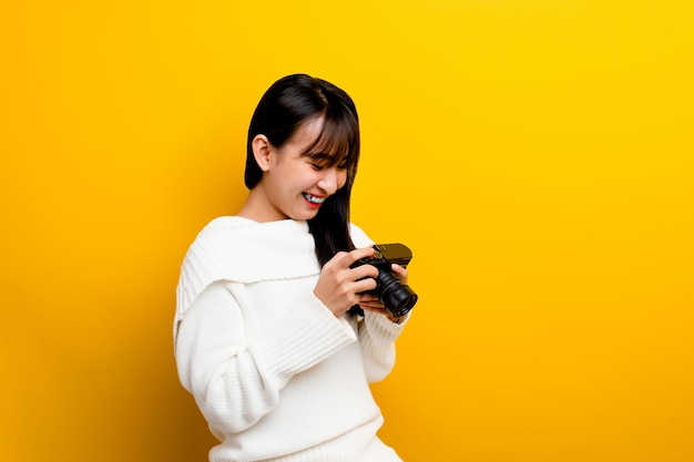 Fotógrafa con cámara a las mujeres jóvenes les encanta tomar fotos amante de la cámara tomando fotos en el estudio amarillo