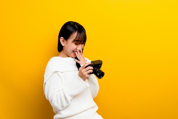 Fotógrafa con cámara a las mujeres jóvenes les encanta tomar fotos amante de la cámara tomando fotos en el estudio amarillo