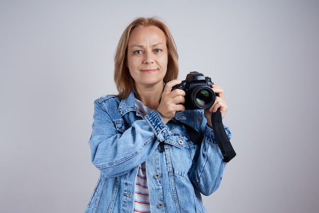 Fotógrafa de mulher madura com câmera fotográfica profissional em fundo cinza