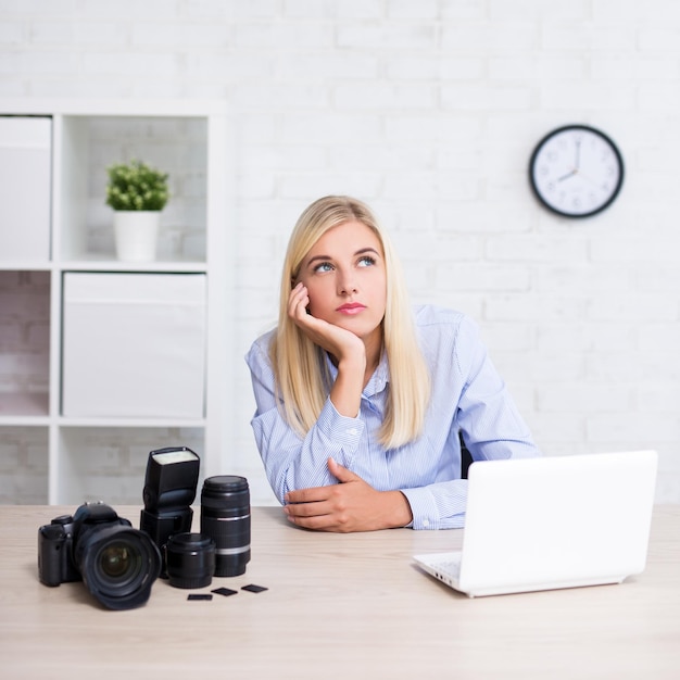 fotógrafa feminina com computador de câmera e equipamento de fotografia pensando em algo