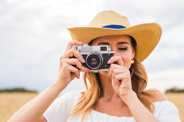 Fotógrafa no campo com uma câmera tirando fotos.