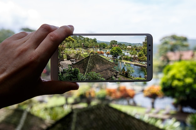 Fotografando com o smartphone na mão. Conceito de viagens. Palácio da Água de Tirta Gangga em Bali.