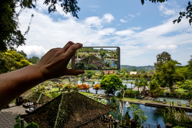 Fotografando com o smartphone na mão. Conceito de viagens. Palácio da Água de Tirta Gangga em Bali.