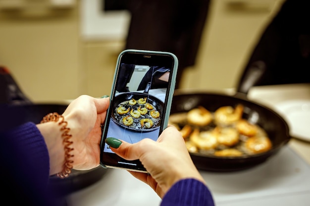 Fotografando comida em um celular smartphone tirando fotos do frango em uma frigideira
