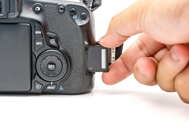 Fotografhand, die moderne Kamera DSLR der Karte SD-codierten Karte hält
