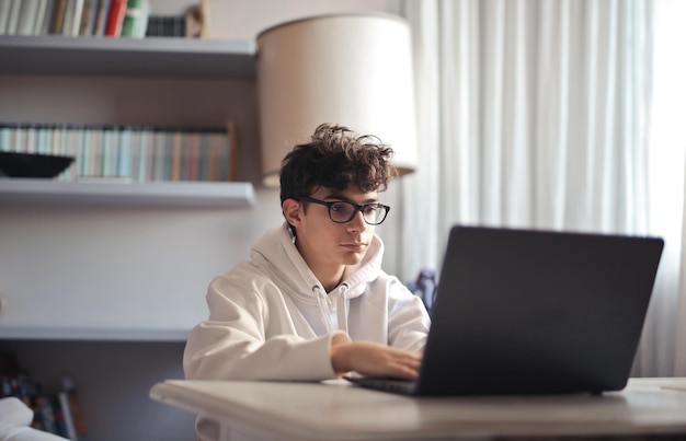 Fotografía de un adolescente con gafas trabajando en la computadora